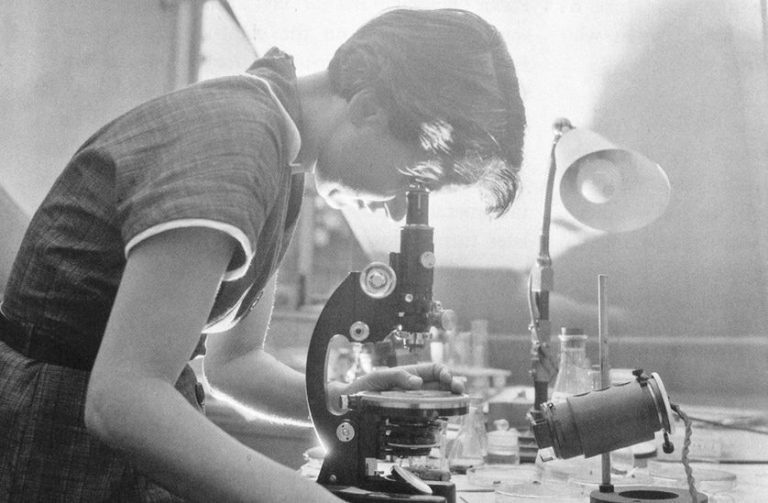 Rosalind Franklin looking into a microscope