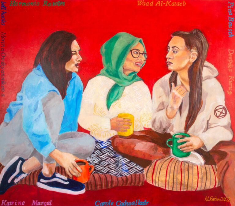 Three young women sit on the floor, talking