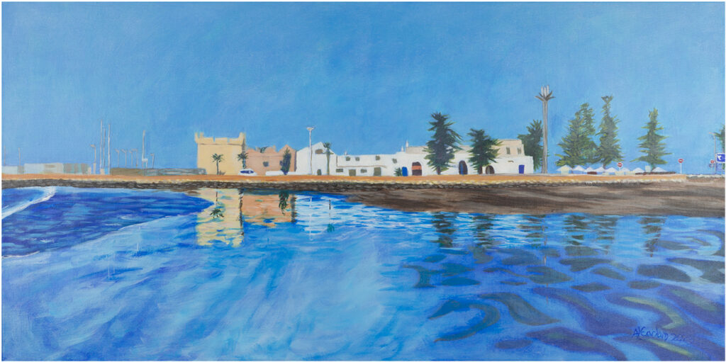 A very blue image of sea, a shoreline with buildings, and sky